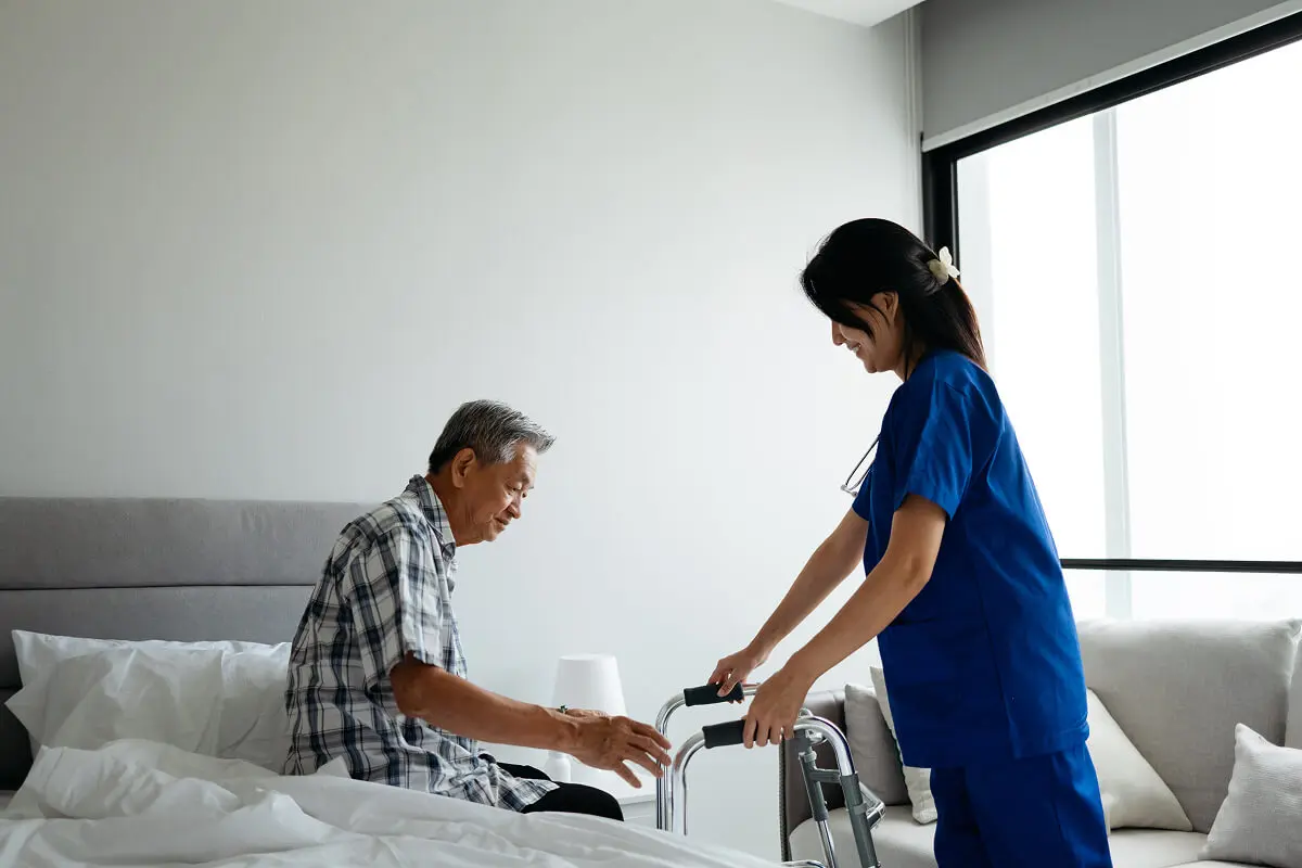 Elderly man assisted by caregiver with walker