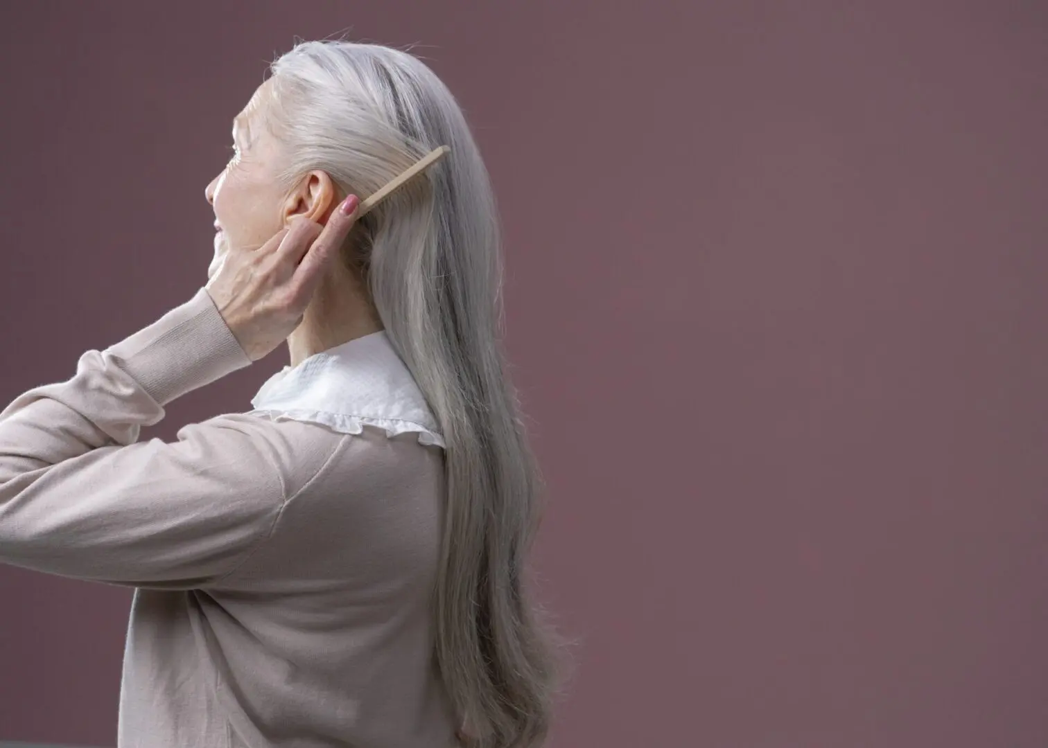 Elderly woman combs her hair