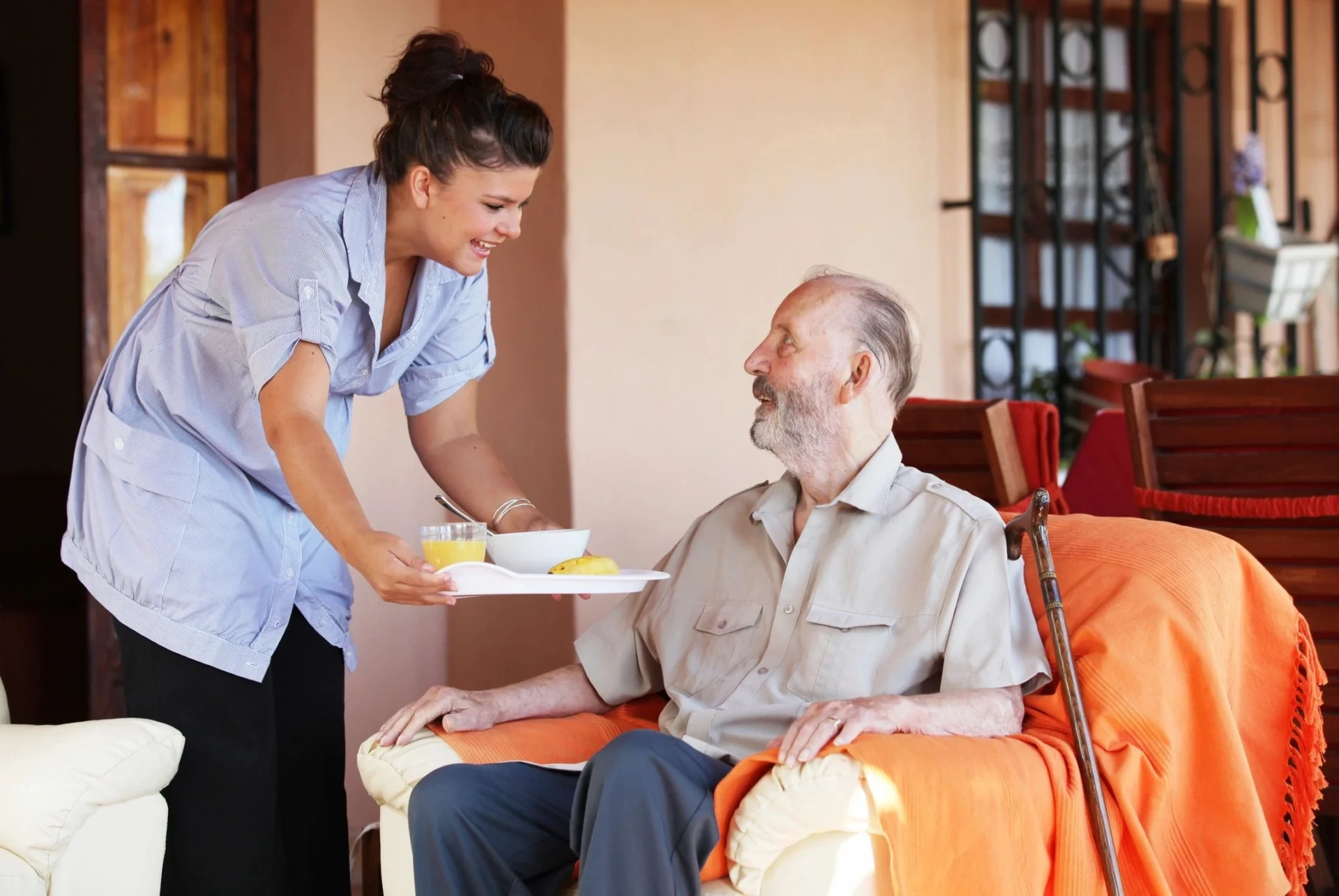 Caregiver serving meal to elderly man