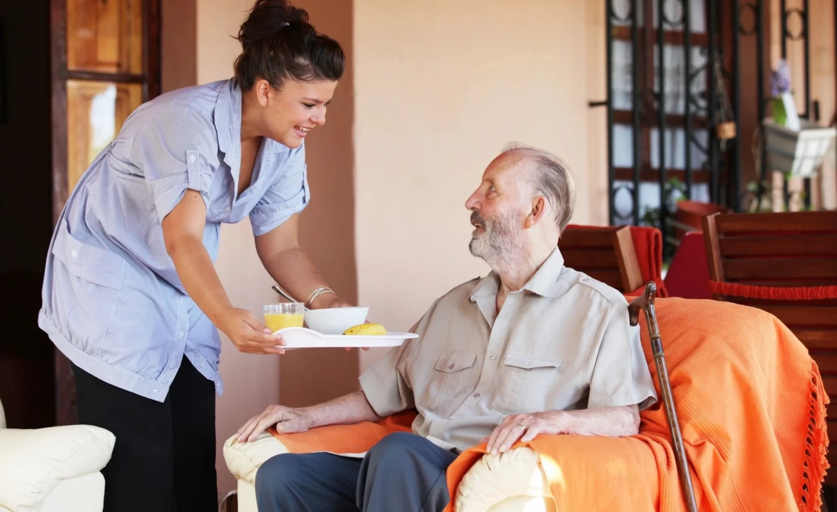 Caregiver serving meal to elderly man