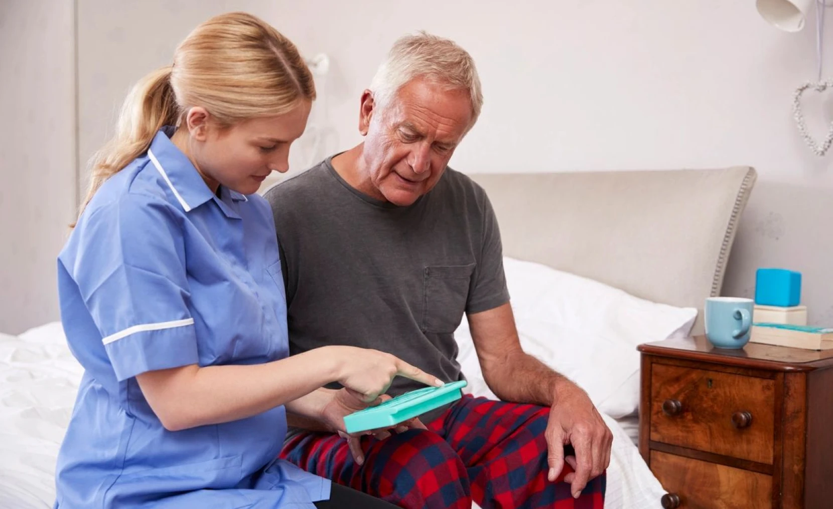Nurse helping senior man with technology
